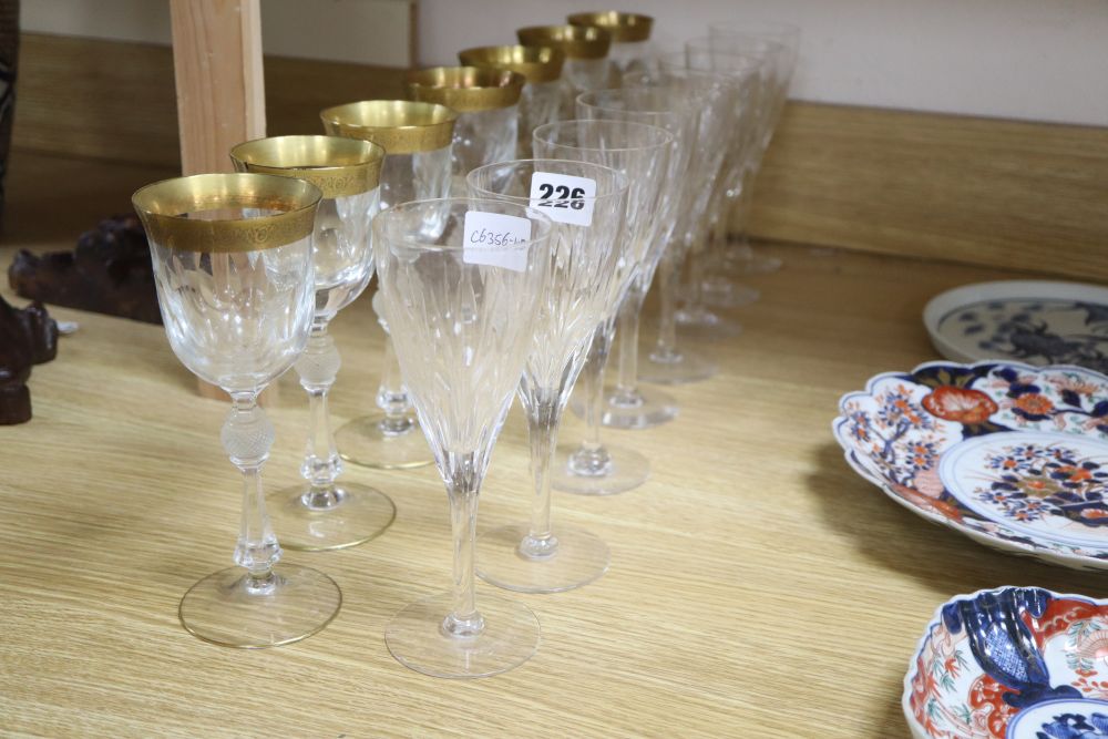 A set of seven gilt rimmed wine glasses and eight glass flutes